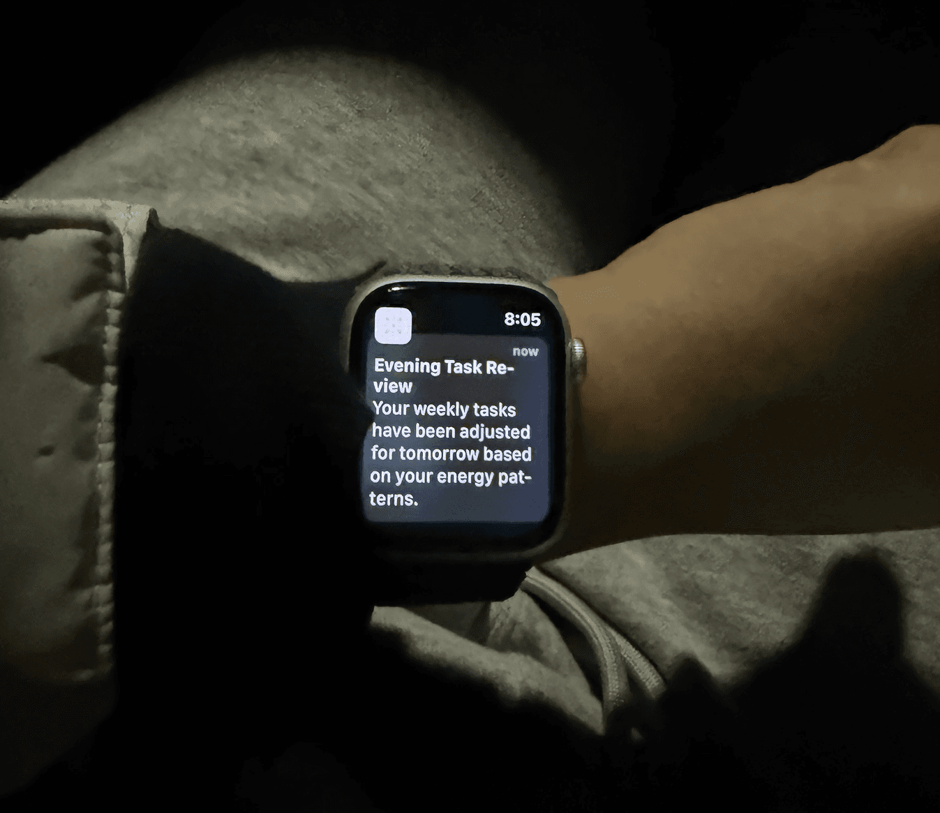 Apple Watch on a wrist at night showing a Fini notification about tasks adjusted for tomorrow